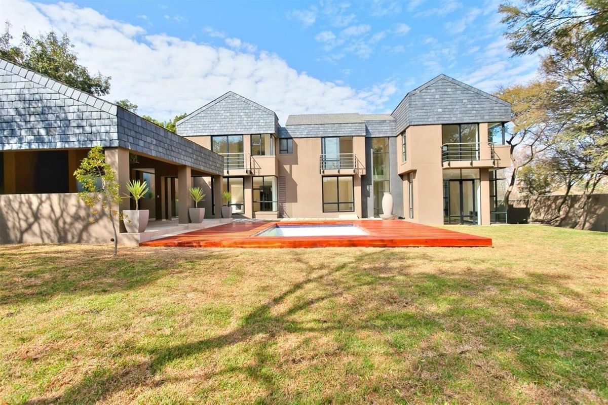 Rear view of a modern multi-level residence featuring a swimming pool with a timber deck, landscaped garden, and balconies.