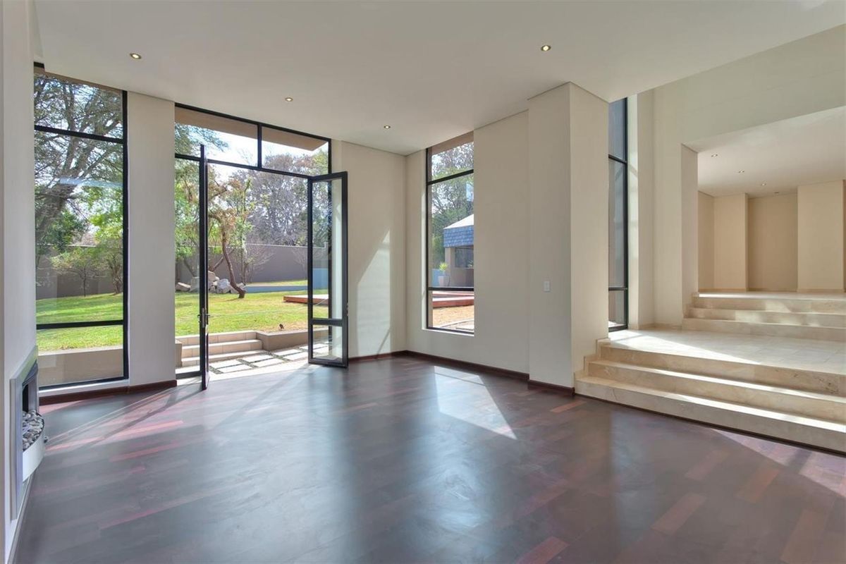 Spacious living area featuring dark hardwood flooring, floor-to-ceiling windows, recessed lighting, and direct access to the rear garden through large glass doors.