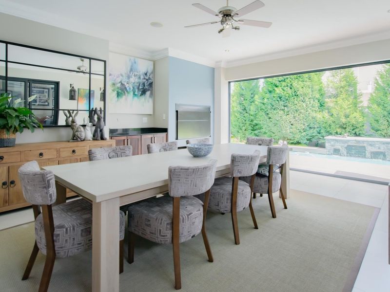 Spacious dining room featuring a built-in fireplace, custom cabinetry, and large sliding glass doors that provide seamless access to the outdoor pool area.