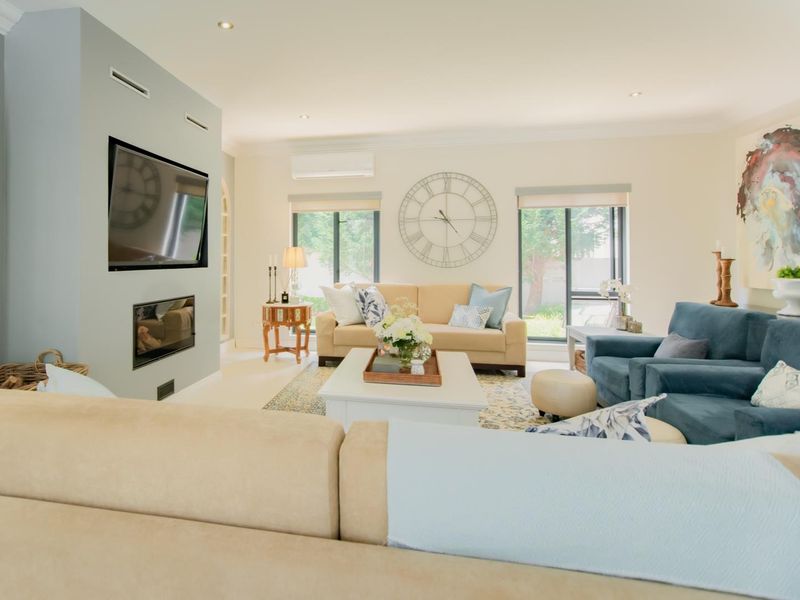 A well-maintained living room featuring a recessed fireplace, split-system air conditioning, and modern recessed downlighting.