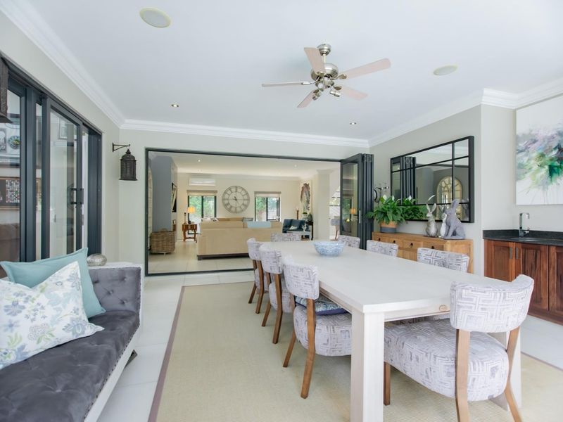 Spacious dining room featuring built-in cabinetry with a sink, recessed lighting, ceiling fan, and large bi-fold doors opening to an adjacent living area.