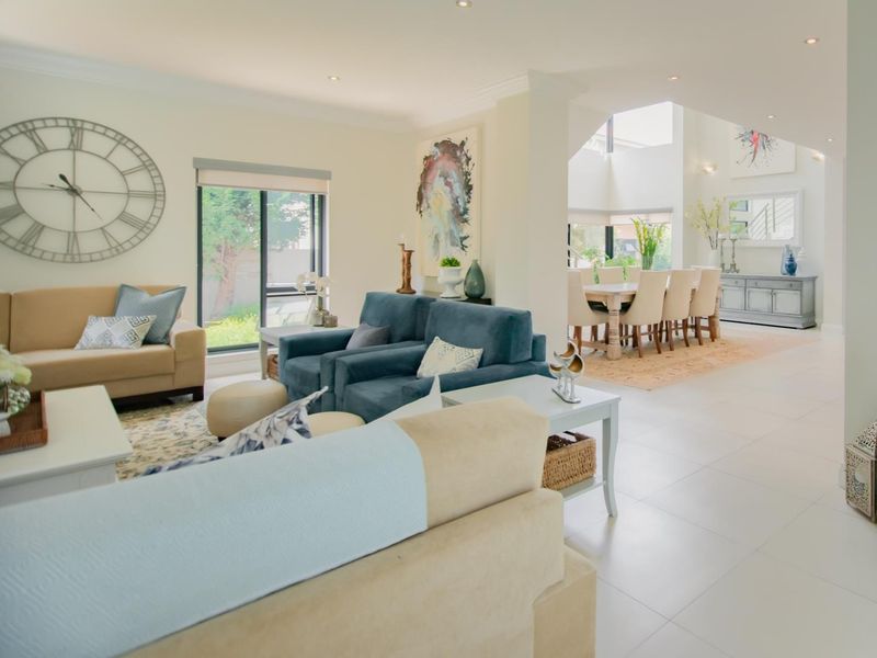 Spacious open-plan living and dining area featuring neutral tiled flooring, recessed lighting, and large windows providing ample natural light.