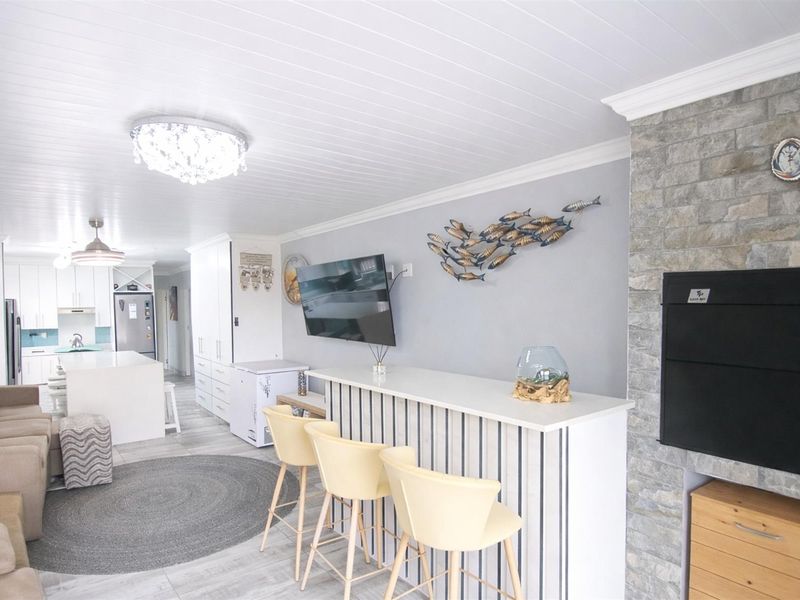 Spacious open-plan living area featuring a stone-clad fireplace, modern kitchen with island, and bright, contemporary finishes throughout.