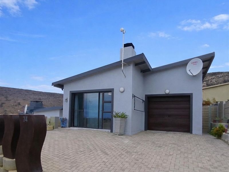 Front elevation of a modern single-story house featuring a paved driveway, integrated single garage, and sliding glass door entrance.