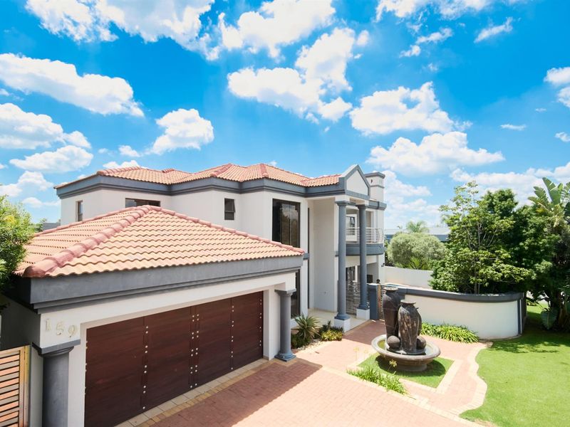 A well-maintained double-story residence featuring a tiled roof, integrated garage, and a landscaped front garden with a decorative water feature.