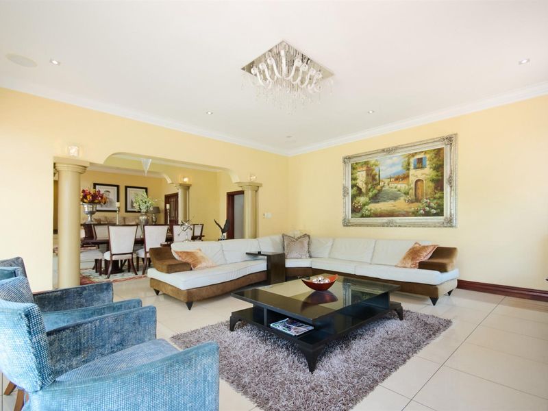 Spacious open-plan living and dining area featuring tiled flooring, decorative columns, and recessed downlighting.