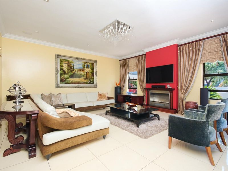 Spacious living room featuring a built-in fireplace with a red accent wall, tiled flooring, and decorative crown molding.