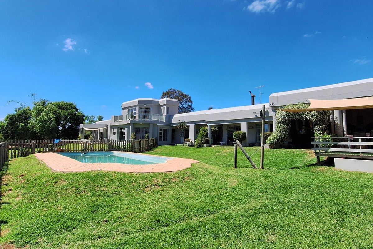 Rear view of the farm property featuring a swimming pool, landscaped lawn, and a covered patio area attached to the main building structure.