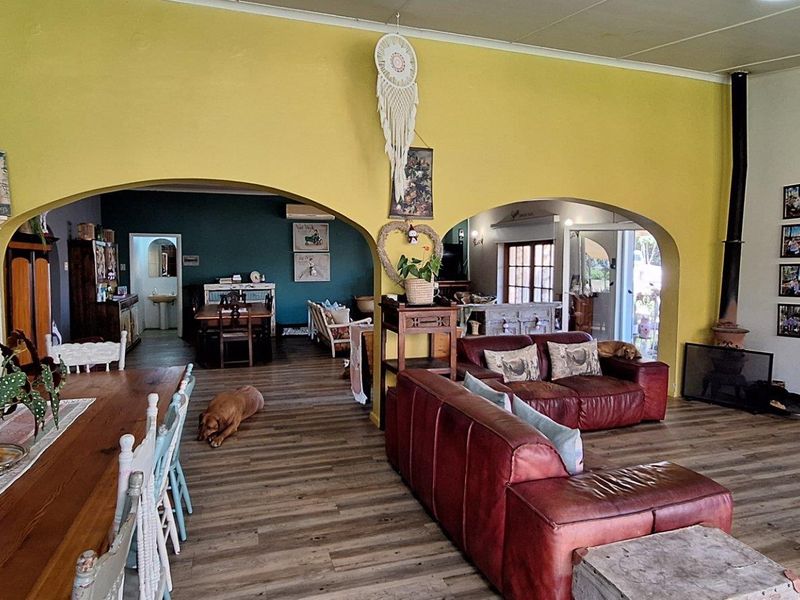 Spacious open-plan living and dining area featuring arched wall openings, wood-look flooring, and a built-in fireplace.