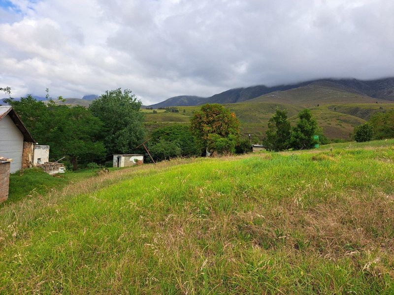 Expansive rural landscape view featuring rolling hills, open pasture, and existing small outbuildings on the property.