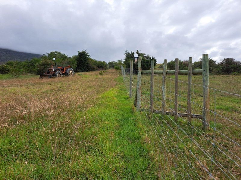 Expansive farm land featuring a wire and timber post boundary fence, set against a natural landscape backdrop.