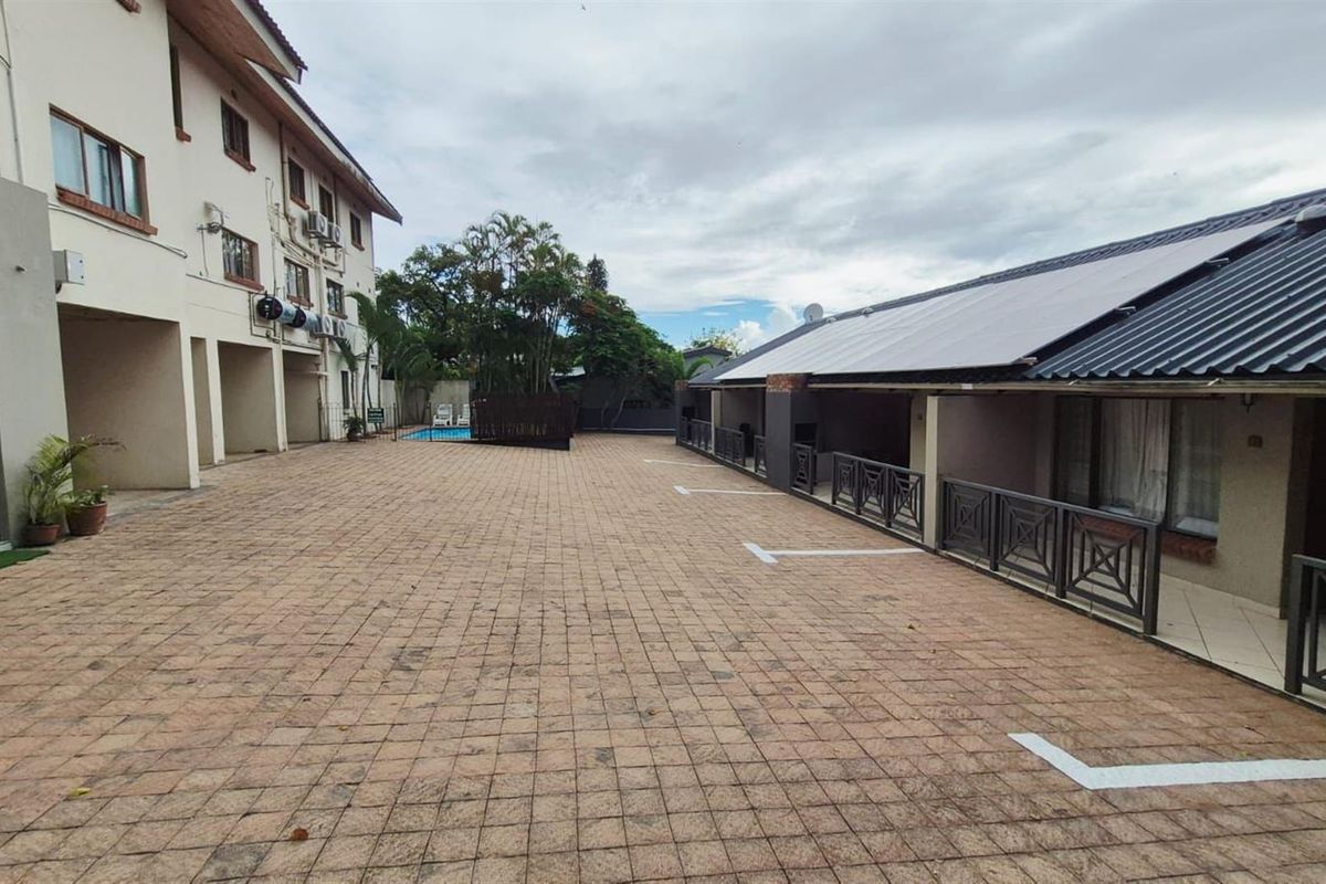 A paved courtyard area within an apartment complex, featuring designated parking spaces and access to a communal pool area.