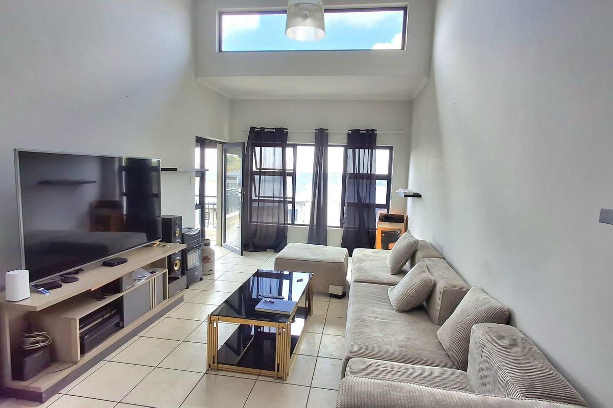 Spacious living room featuring high ceilings with clerestory windows, tiled flooring, and direct access to an outdoor balcony area.