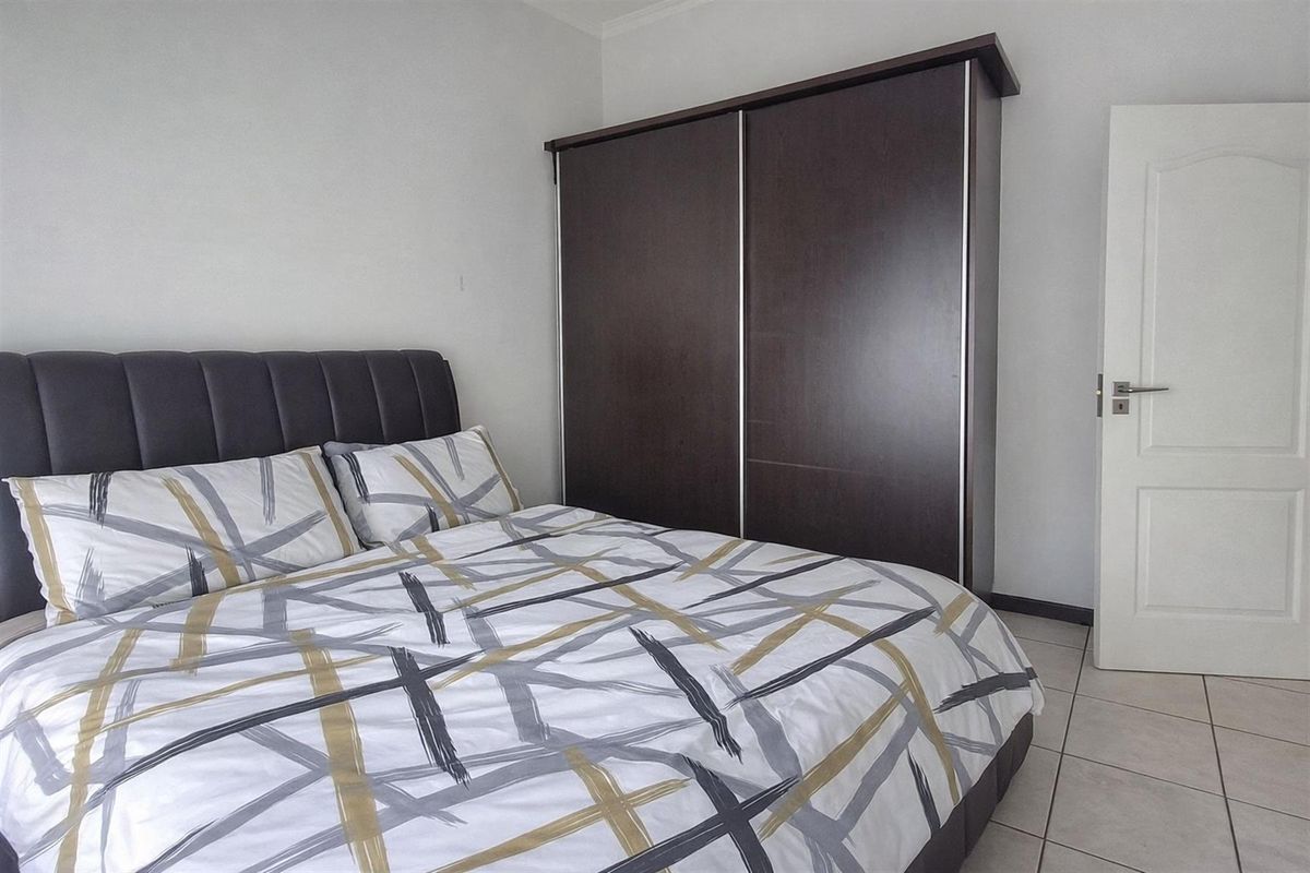 A bedroom featuring tiled flooring and a built-in dark wood sliding door wardrobe.