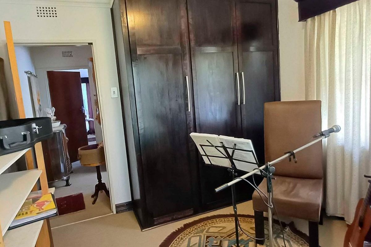 A bedroom featuring a large dark wood built-in wardrobe and neutral carpeting, offering a functional space with potential for modernization.