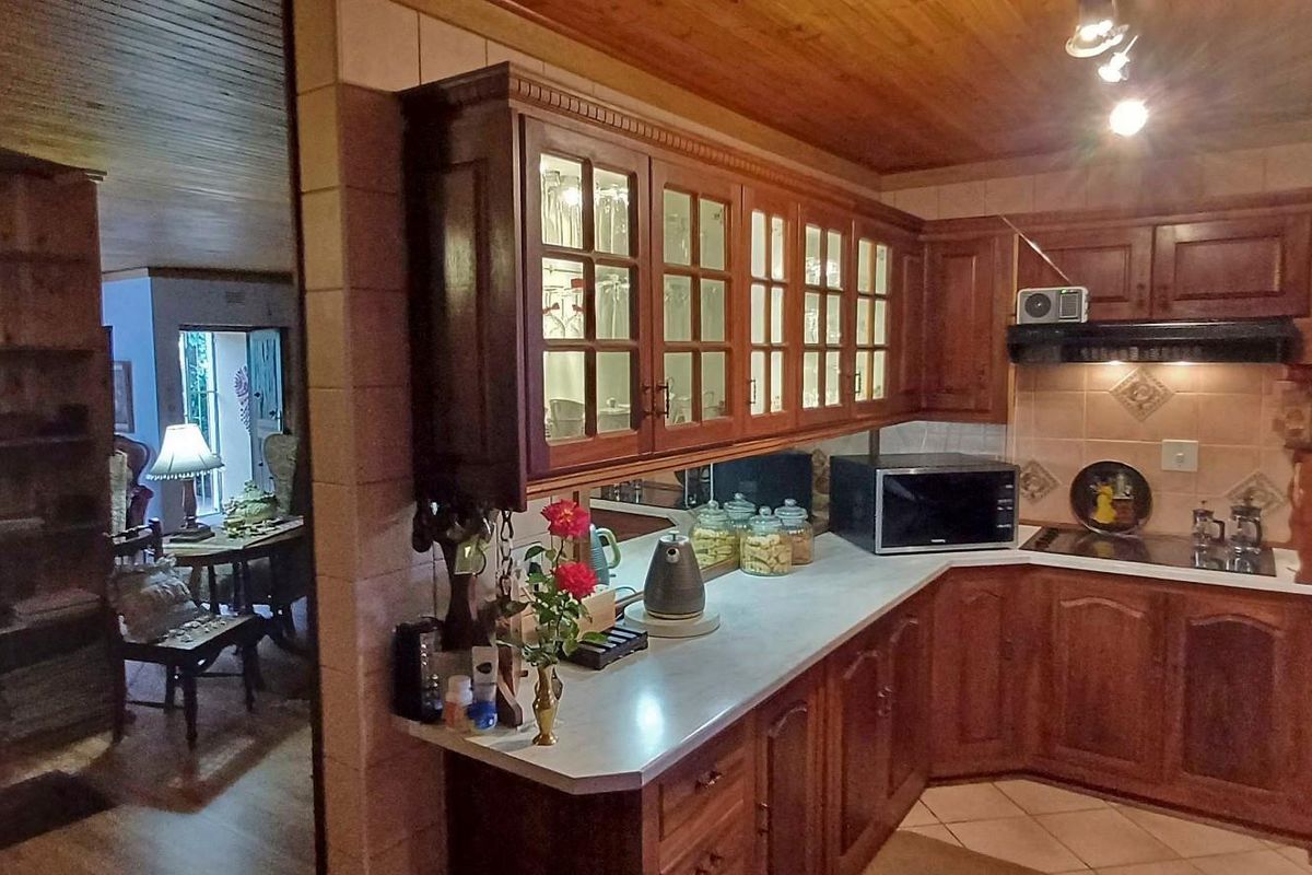 A traditional kitchen featuring extensive timber cabinetry, glass-fronted display units, built-in appliances, and a warm timber-clad ceiling, offering a classic and functional workspace.