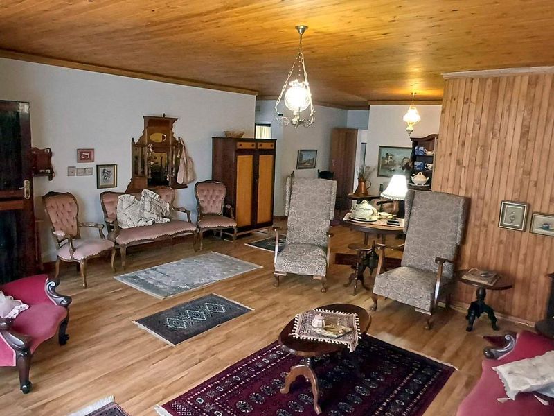 Spacious living area featuring warm timber ceiling, wood wall paneling, and timber flooring, offering a traditional and cozy atmosphere.