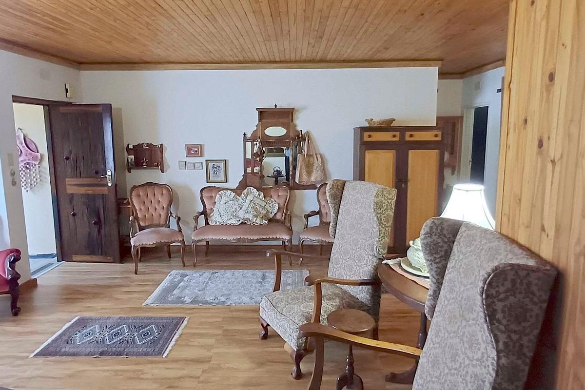 A living room featuring timber ceiling paneling and laminate flooring, providing a traditional aesthetic with potential for modern updates.