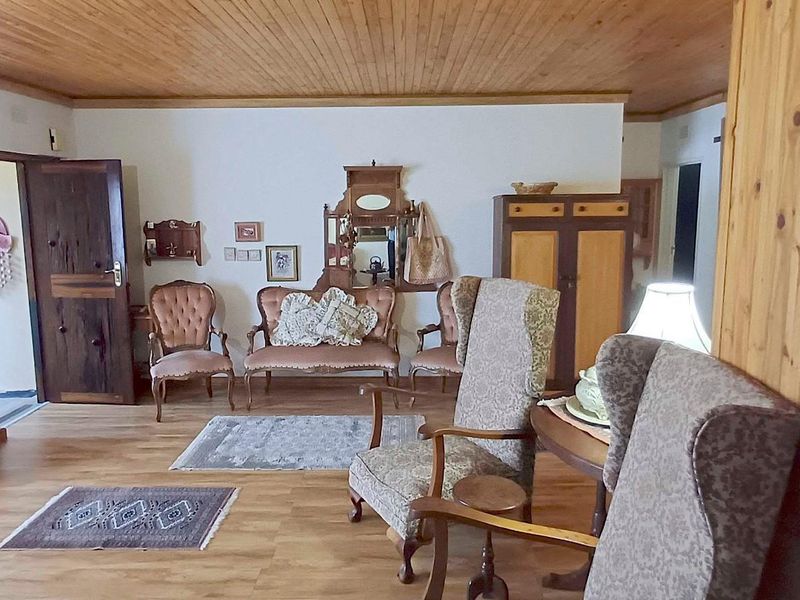 A living room featuring timber ceiling paneling and laminate flooring, providing a traditional aesthetic with potential for modern updates.