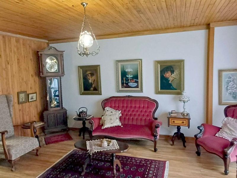 A traditional living room featuring timber-paneled walls and ceiling with laminate flooring, offering a classic aesthetic ready for a modern update.