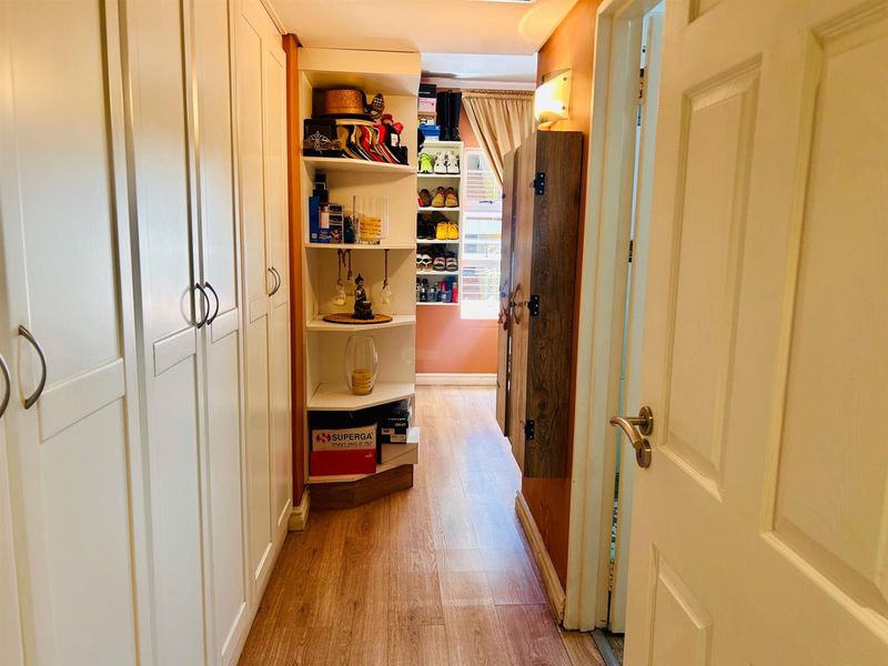 A functional hallway featuring extensive built-in floor-to-ceiling cabinetry, providing ample storage space with a warm wood-look laminate floor finish.