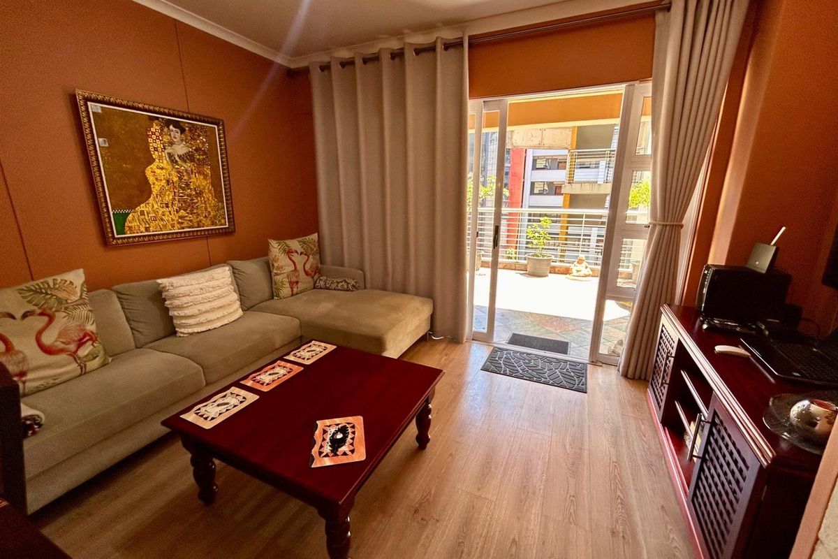A living room featuring wood-look flooring and a sliding glass door that opens onto a private balcony.