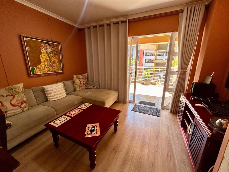 A living room featuring wood-look flooring and a sliding glass door that opens onto a private balcony.