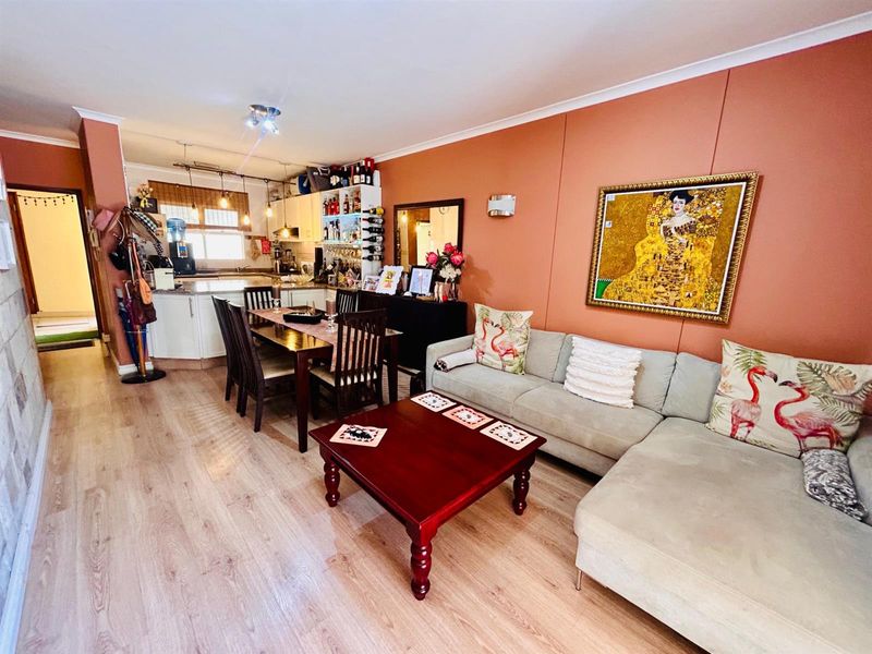 Open plan living and dining area featuring laminate flooring and an integrated kitchen with built-in cabinetry.