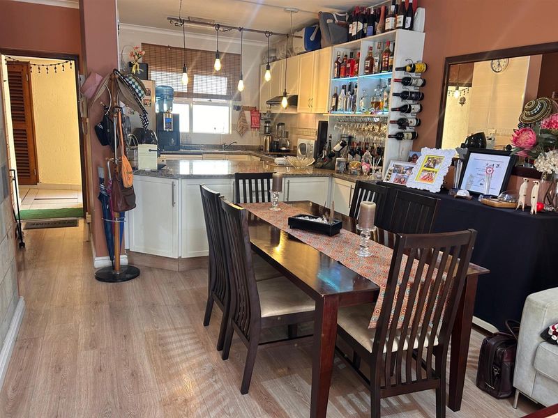 Open-plan kitchen and dining area featuring granite countertops, built-in cabinetry, and laminate flooring, creating a functional and connected living space.