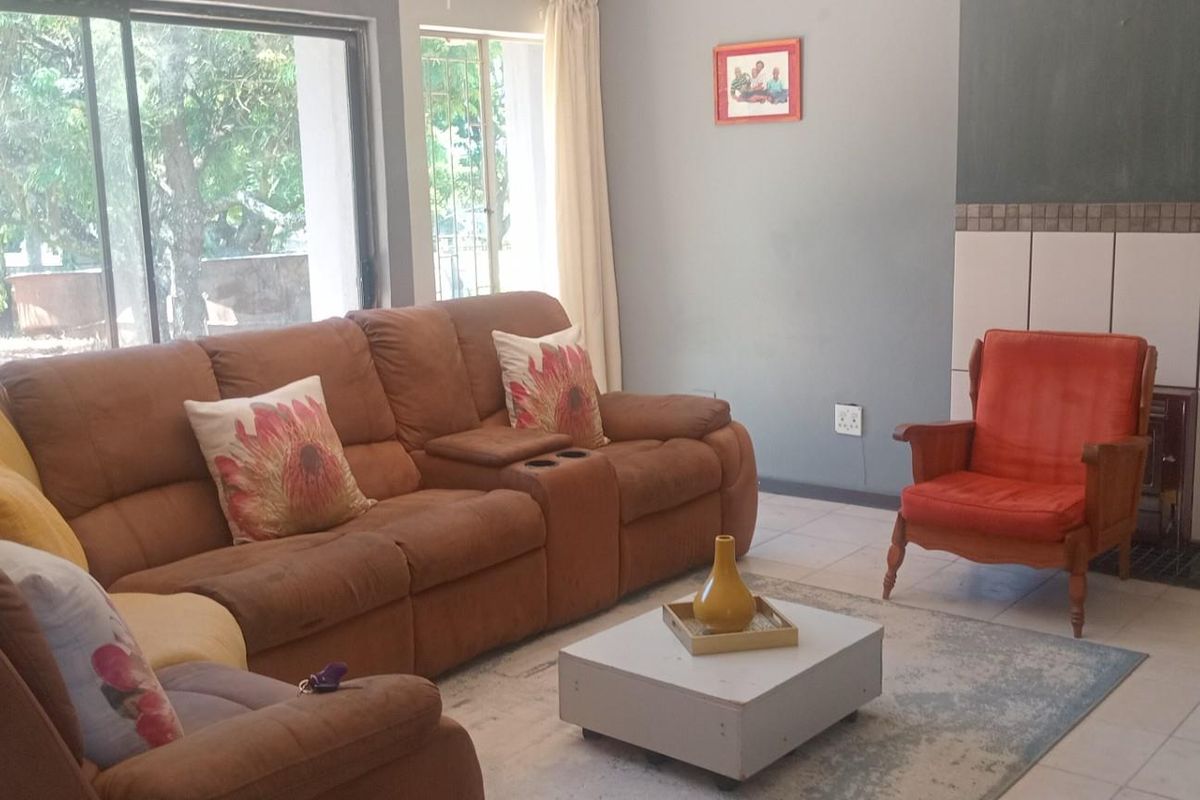 A living room featuring tiled flooring, a built-in fireplace with tiled surround, and large sliding glass doors providing access to the outdoor area.