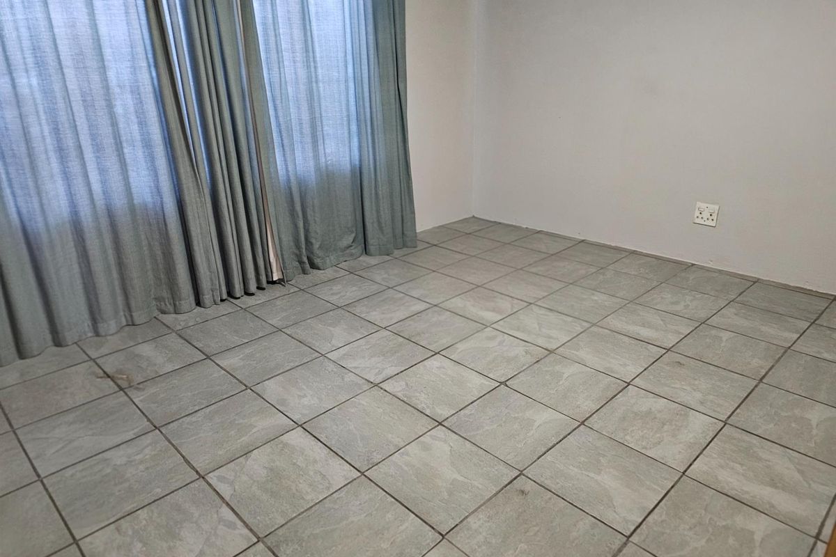 A vacant room featuring neutral grey floor tiles and floor-to-ceiling curtains, providing a blank canvas for interior design.