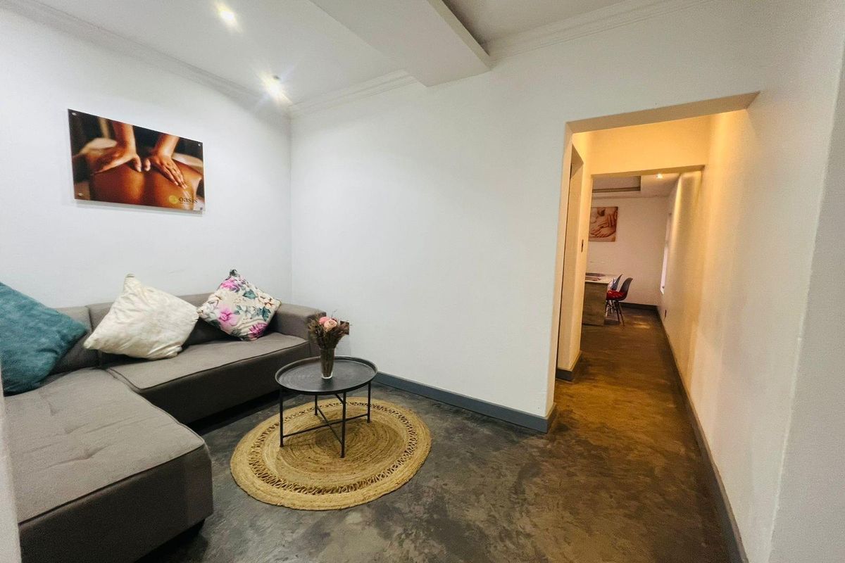 A functional waiting or reception area featuring polished concrete flooring, recessed ceiling lighting, and a transition into an adjoining hallway space.