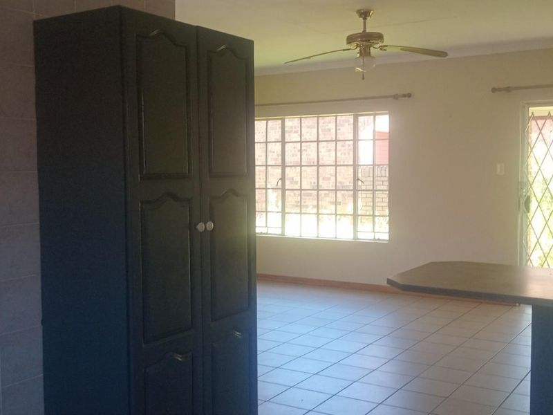 Open plan living area featuring tiled flooring, a ceiling fan, and sliding door access to the exterior.