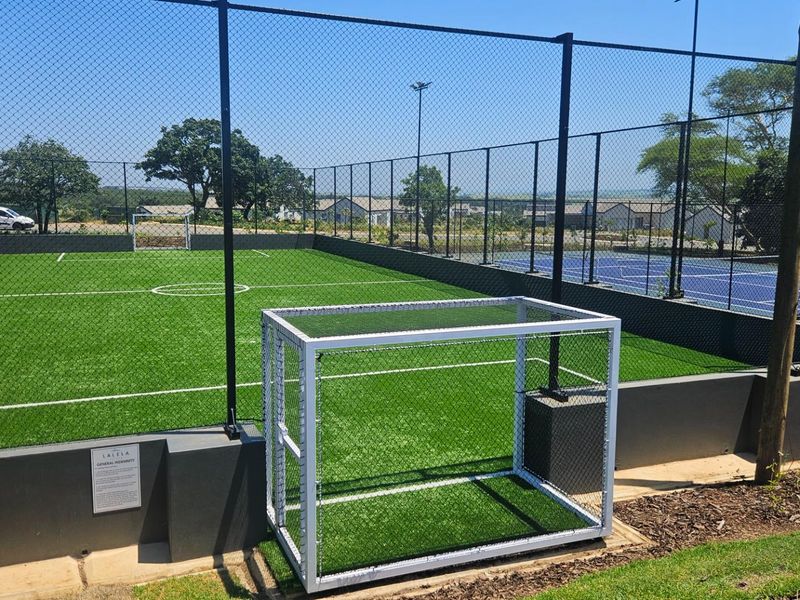 A well-maintained outdoor sports facility featuring artificial turf, soccer goal posts, and secure chain-link perimeter fencing.