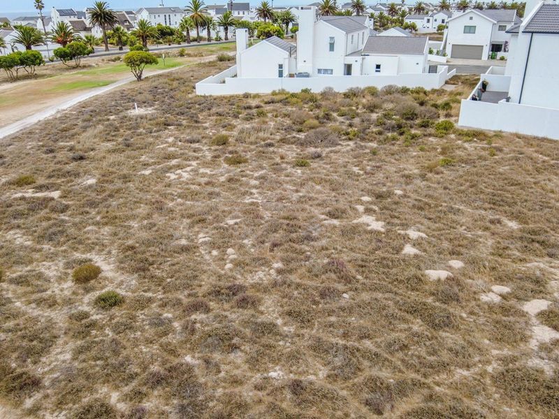An elevated aerial view of a vacant residential plot situated in a developed coastal estate, ready for new construction.
