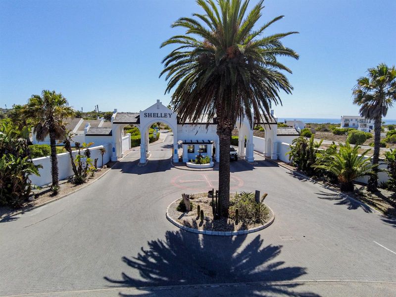 Aerial view of the secure gated entrance to the Shelley residential estate, featuring a paved driveway, guardhouse, and landscaped roundabout.
