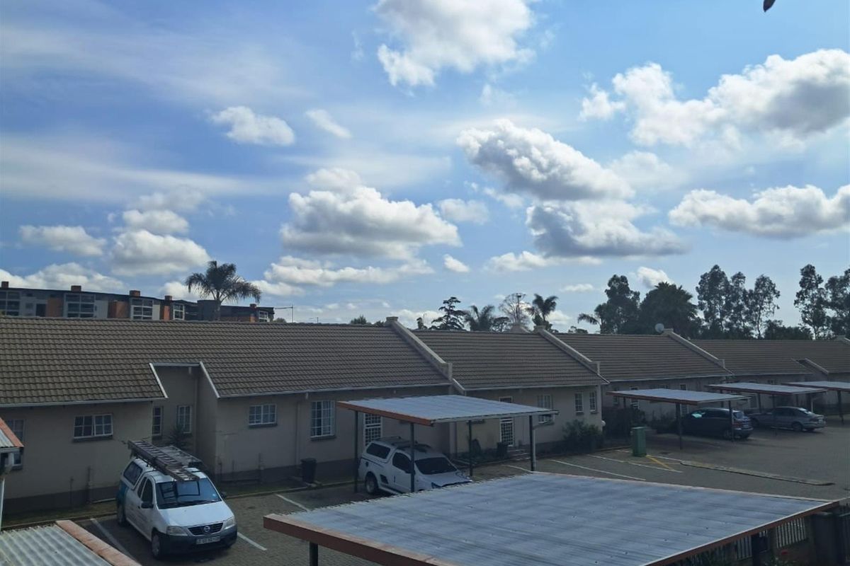 An elevated view of the apartment complex exterior, featuring tiled roofing, paved parking areas, and covered carports.