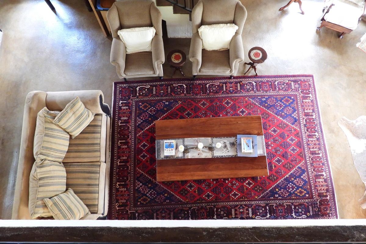 An overhead view of a living area featuring polished concrete floors and a staircase, providing a clear perspective of the room's layout.