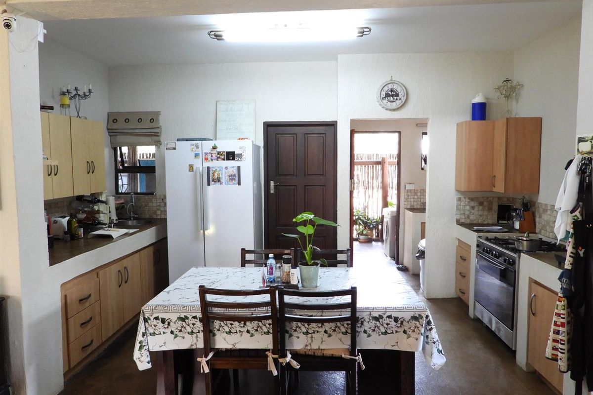 Functional kitchen featuring built-in cabinetry, a stainless steel stove, and a tiled backsplash, with direct access to an adjacent utility area.
