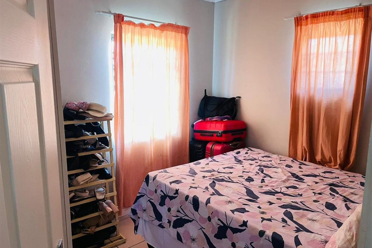 A functional bedroom featuring tiled flooring and decorative ceiling cornicing, providing a neutral base for potential interior updates.