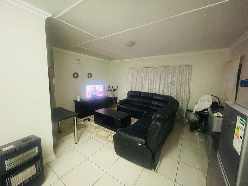 A functional living room featuring tiled flooring and standard ceiling finishes, providing a neutral base for potential interior updates.