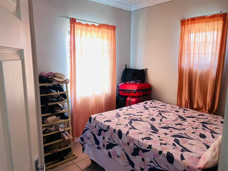 A functional bedroom featuring tiled flooring and decorative ceiling cornicing, providing a neutral base for potential interior updates.