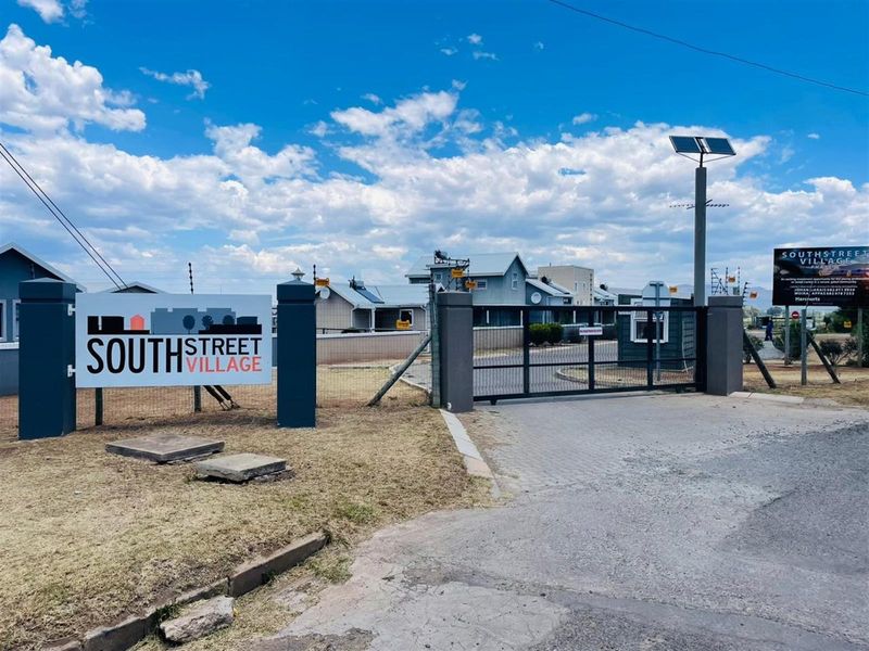 Entrance view of South Street Village featuring a secure gated access point with electric fencing and solar lighting.