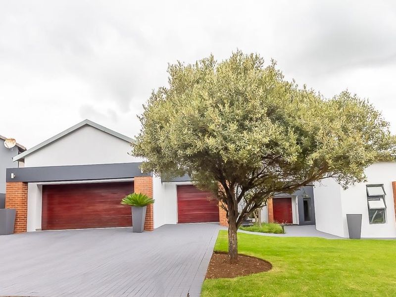 A well-maintained modern home exterior featuring a double garage, paved driveway, and neat front garden with contemporary architectural finishes.
