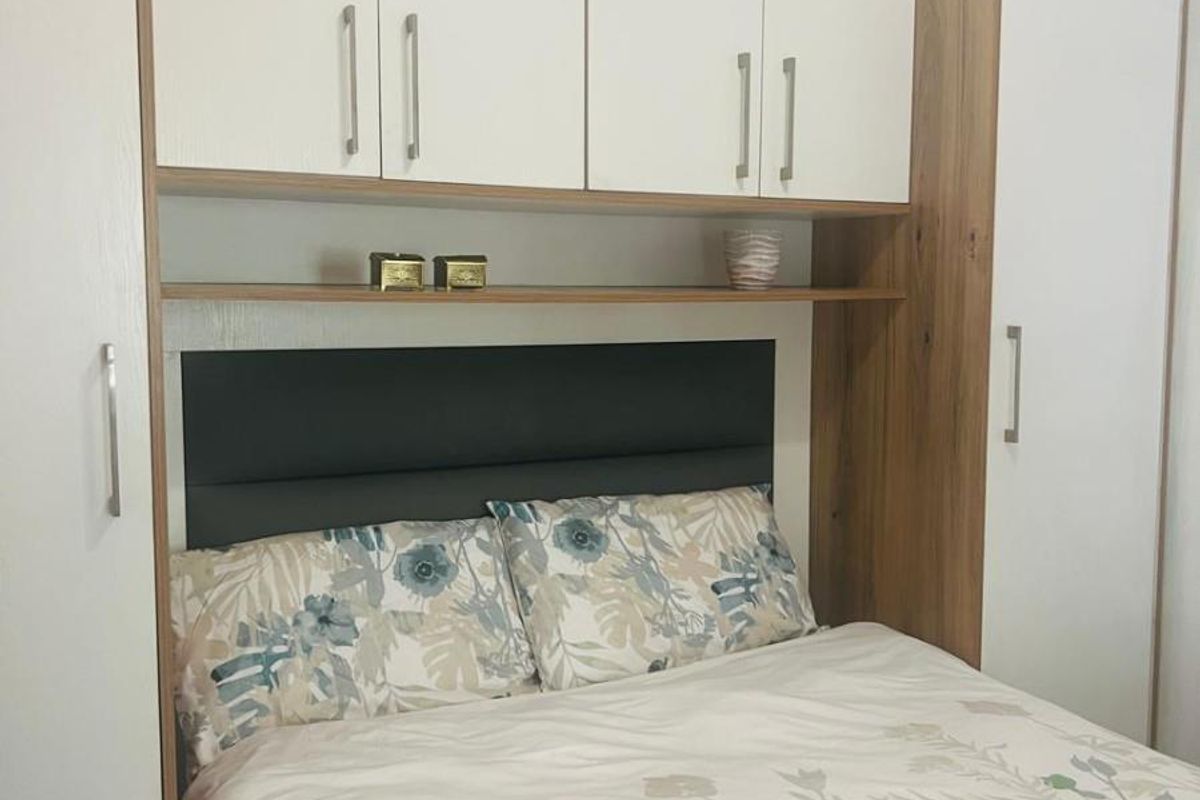 A bedroom featuring custom built-in cabinetry with overhead storage and an integrated headboard, providing efficient use of space.