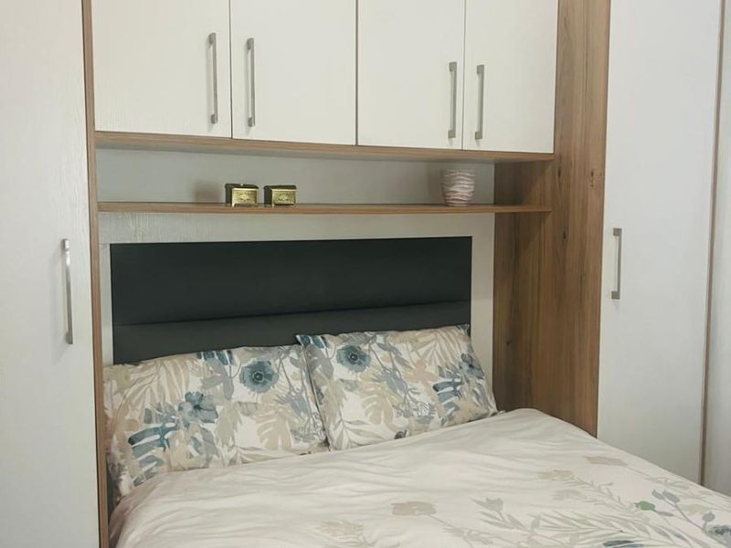 A bedroom featuring custom built-in cabinetry with overhead storage and an integrated headboard, providing efficient use of space.