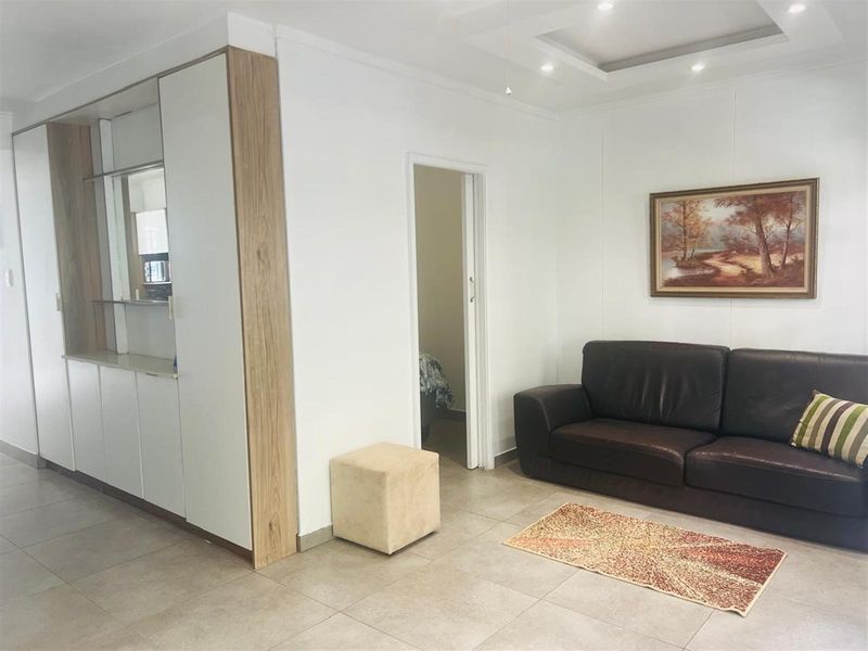 A well-maintained living area featuring neutral tiled flooring, recessed ceiling lighting, and integrated built-in cabinetry.