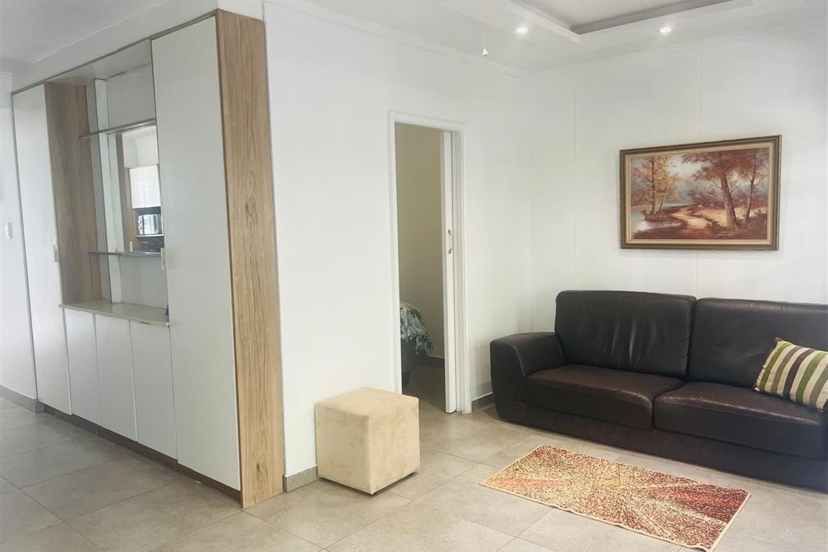 A well-maintained living area featuring neutral tiled flooring, recessed ceiling lighting, and integrated built-in cabinetry.
