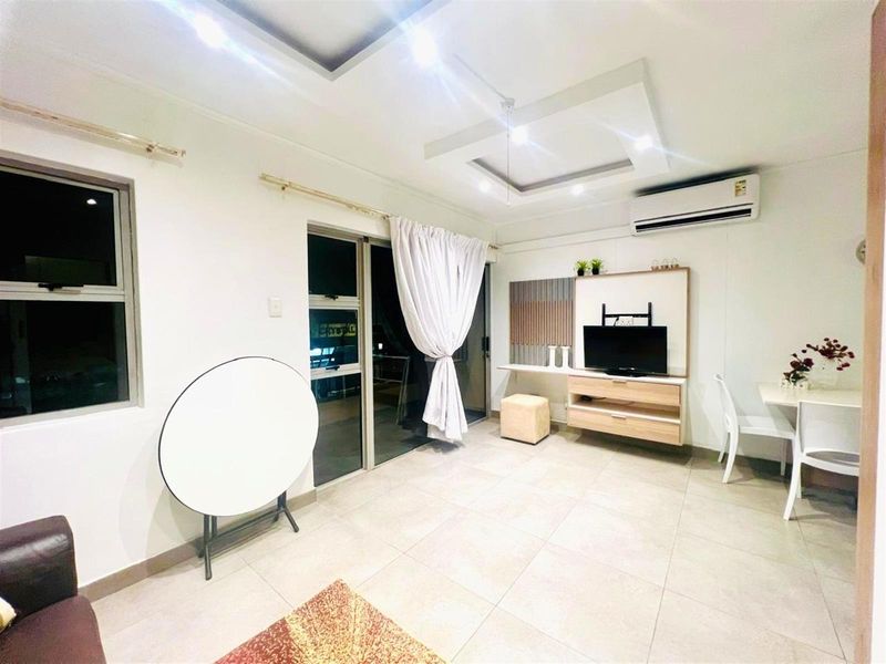 A bright living room featuring tiled flooring, a recessed ceiling with downlights, a wall-mounted air conditioner, and a sliding glass door leading outside.
