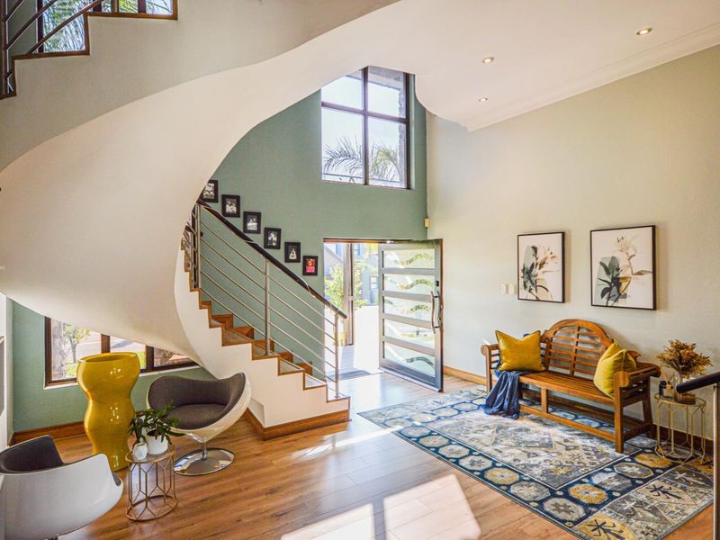 Spacious double-volume entrance hall featuring a striking spiral staircase, modern laminate flooring, and a large window providing abundant natural light.